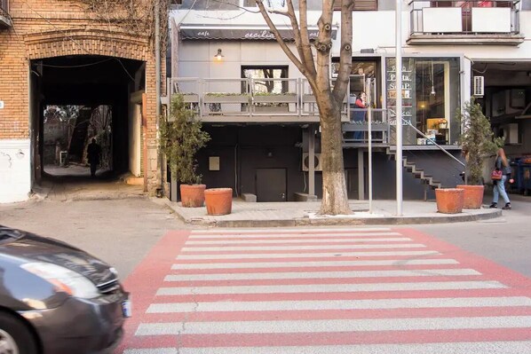 A street view with a pedestrian crossing, a building with a cafe named 'cafe', and a staircase leading to an upper floor.