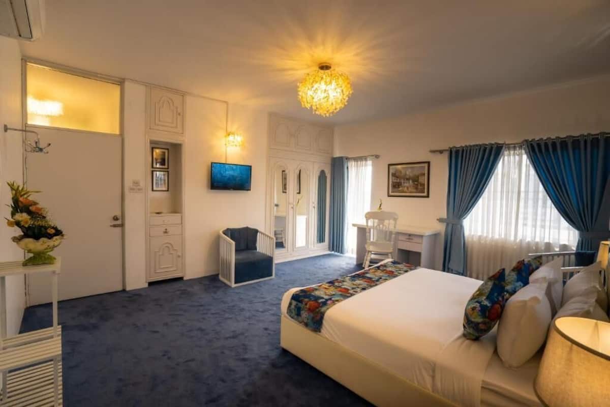 Ein Hotelzimmer mit einem großen Bett, einem Schreibtisch, einem Stuhl, einem Fernseher und einer Kronleuchter.