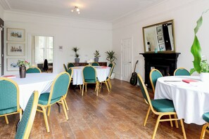 A dining room with a white table, green upholstered chairs, and a fireplace. - EBS London Stay (London)