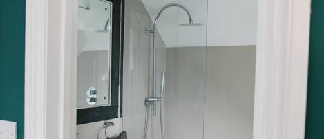 A bathroom with a shower, sink, and mirror.