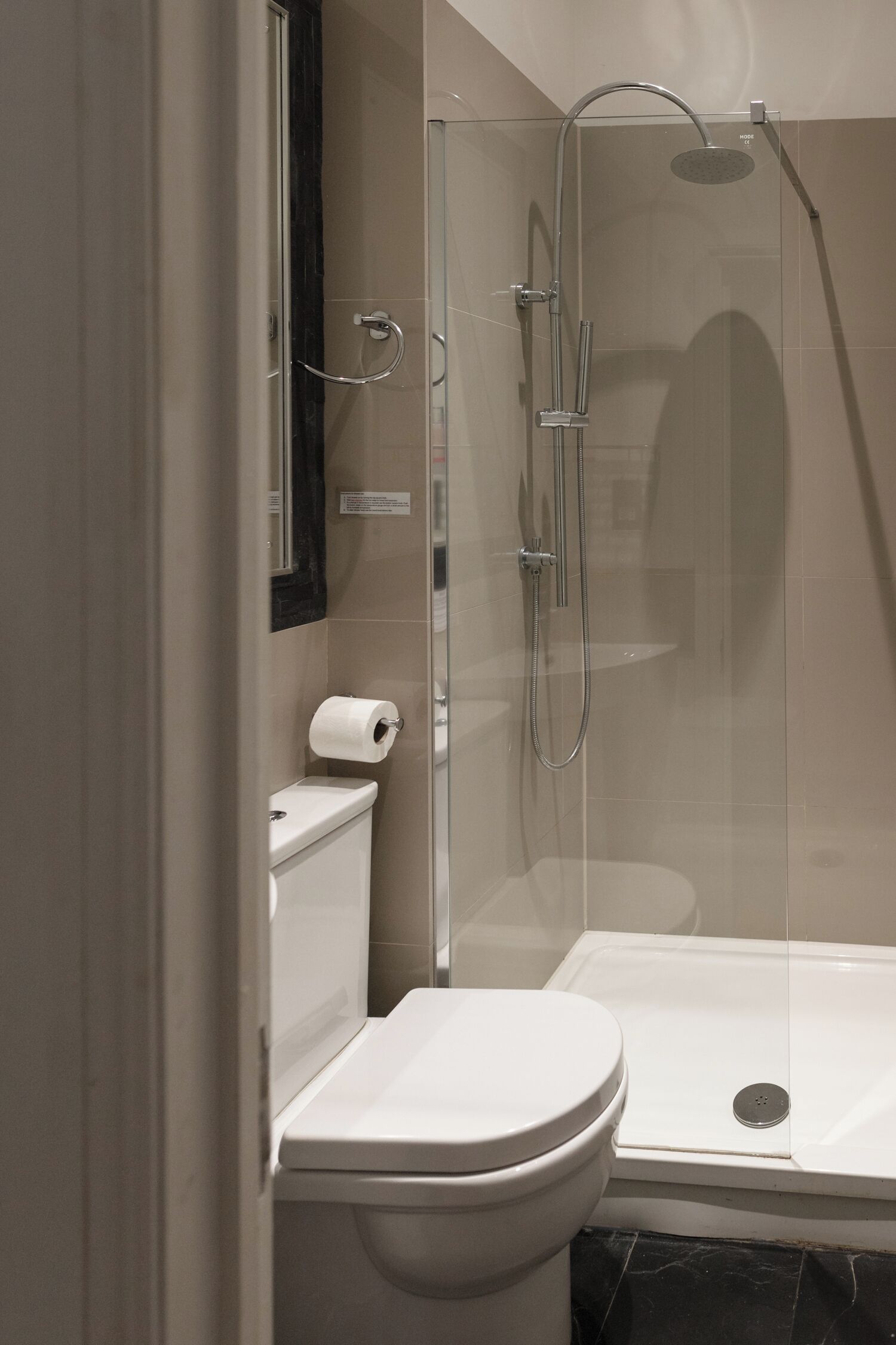 A modern bathroom with a glass-enclosed shower, a toilet, and a sink.