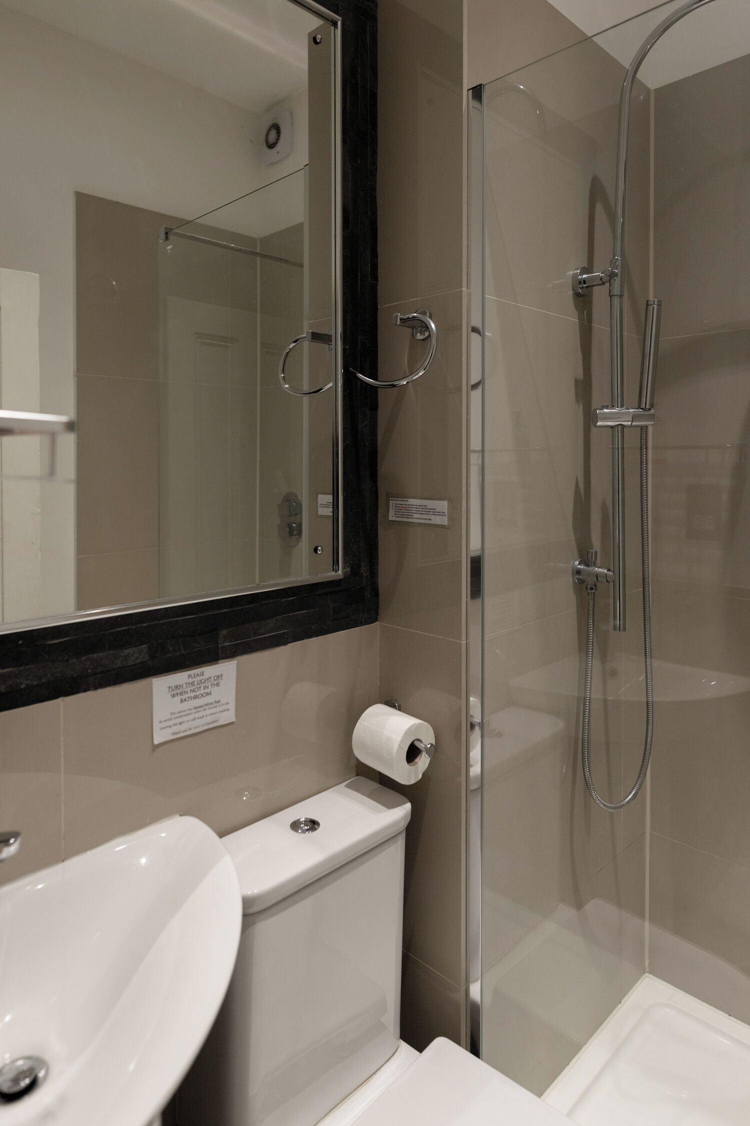 A bathroom with a glass-enclosed shower, a toilet, and a sink.
