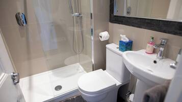 Un baño con ducha de vidrio, inodoro y lavabo.