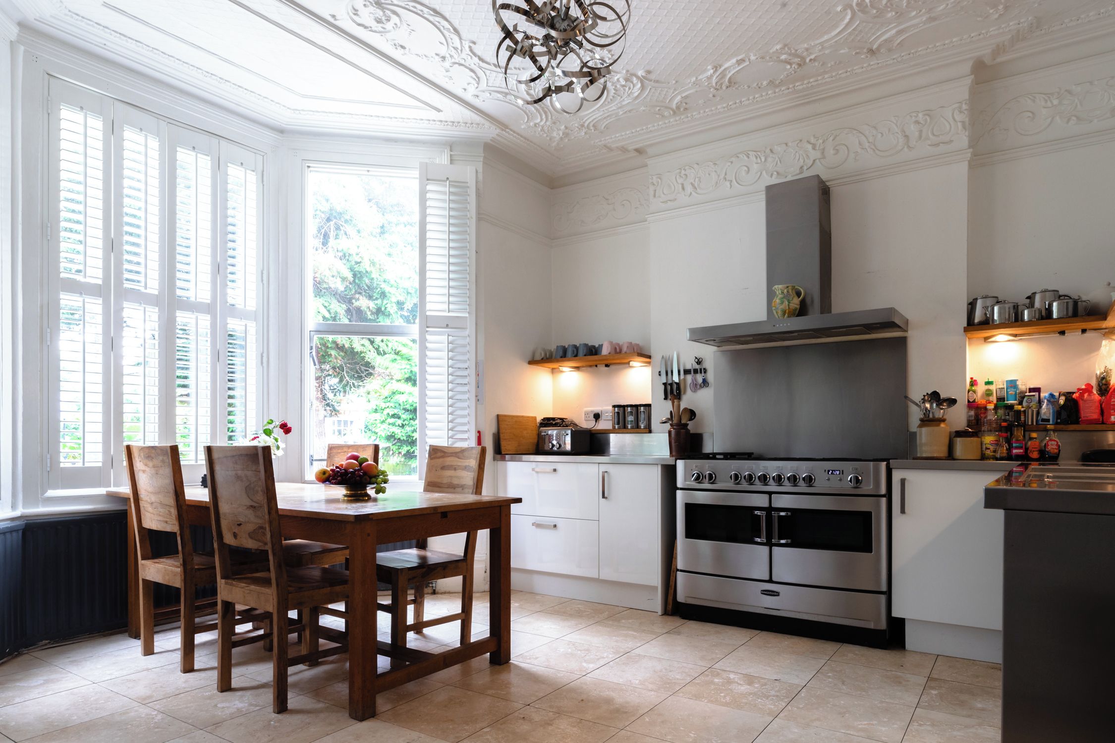 A kitchen with a large stove, white cabinetry, and a dining area with wooden chairs and a table.