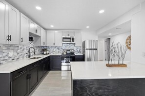 Kitchen with cabinets, 4-burner stove with oven, refrigerator, microwave, kettle, and sink. Additionally, there is a kitchen island for added convenience. - Family 3BR Getaway • Orlando Fun & Attractions (Oviedo)