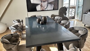 Un comedor moderno con una mesa oscura, sillas acolchadas y un cuadro grande en la pared.
