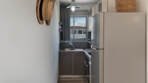 A compact kitchen with a built-in refrigerator, a sink, and a window with a view of buildings. - Phaedrus Living Nicosia Heartside Flat  (Strovolos)