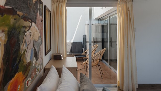 A modern hotel room with a large bed, a small table, a chair, and a balcony with a glass door. - Phaedrus Living Nicosia Heartside Flat  (Strovolos)
