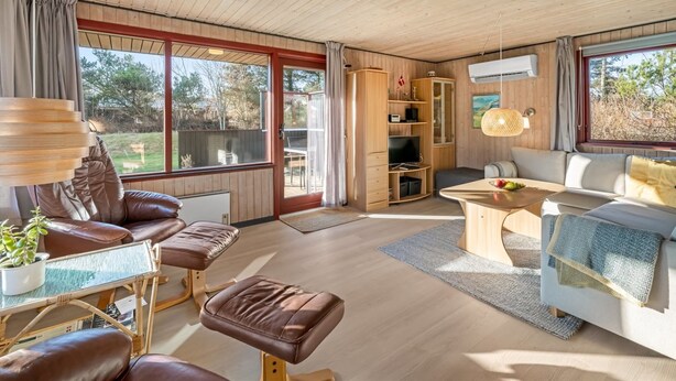 Een ruime woonkamer met een groot raam, een bank, een salontafel en een boekenkast.