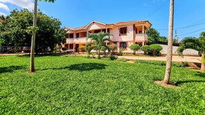 A two-story house with a balcony, surrounded by a well-maintained lawn and palm trees. - DIANI BEACH GOLD APARTMENTS  (Diani Beach)