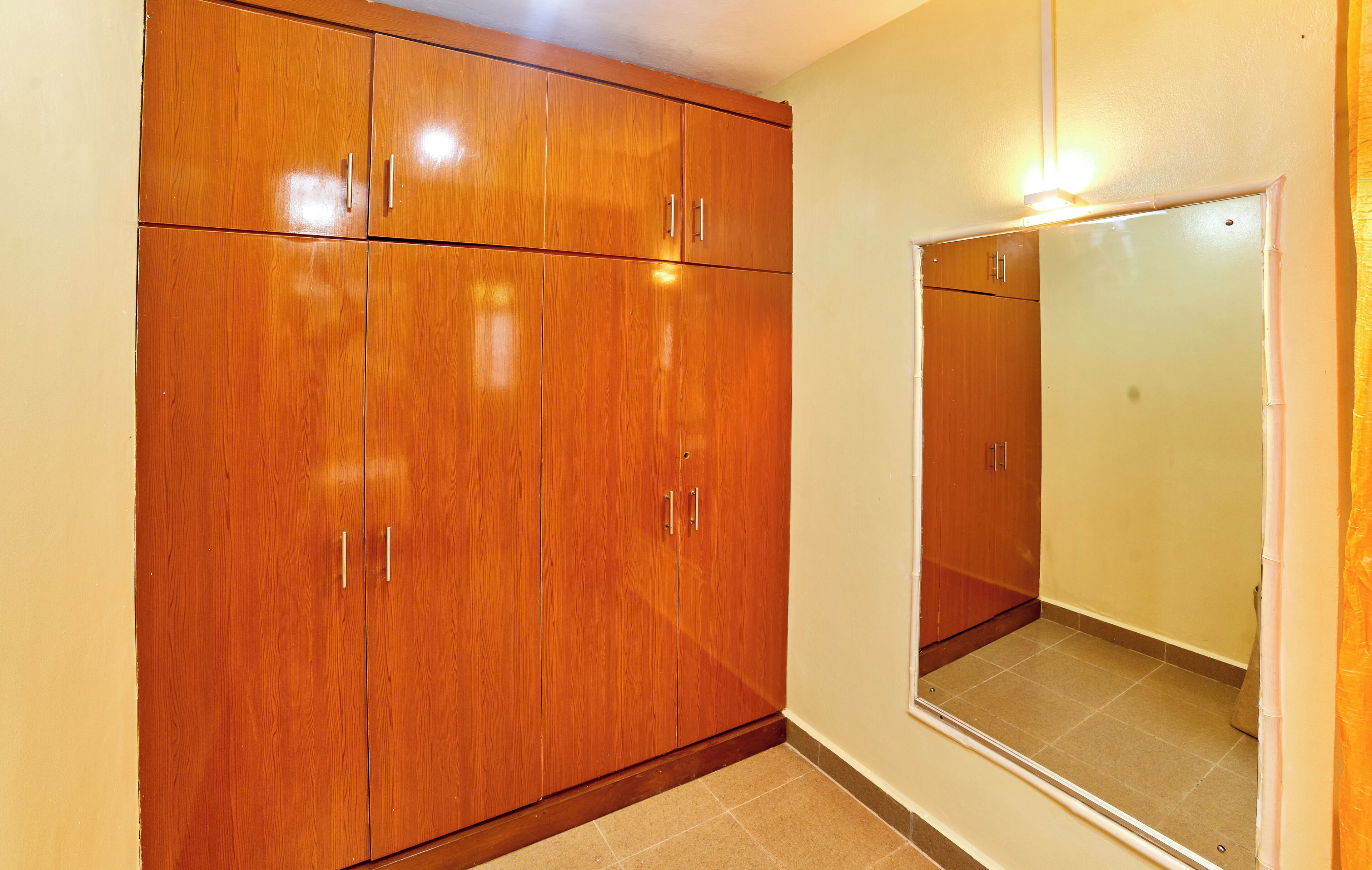 A hallway with wooden wardrobe cabinets and a mirror on the wall.