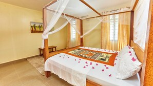 A four-poster bed with a canopy, a small bedside table, and a decorative rug. - DIANI BEACH GOLD APARTMENTS  (Diani Beach)