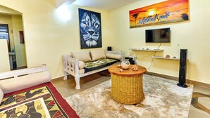 A living room with a sofa, a coffee table, a flat-screen TV, and artwork on the walls. - DIANI BEACH GOLD APARTMENTS  (Diani Beach)