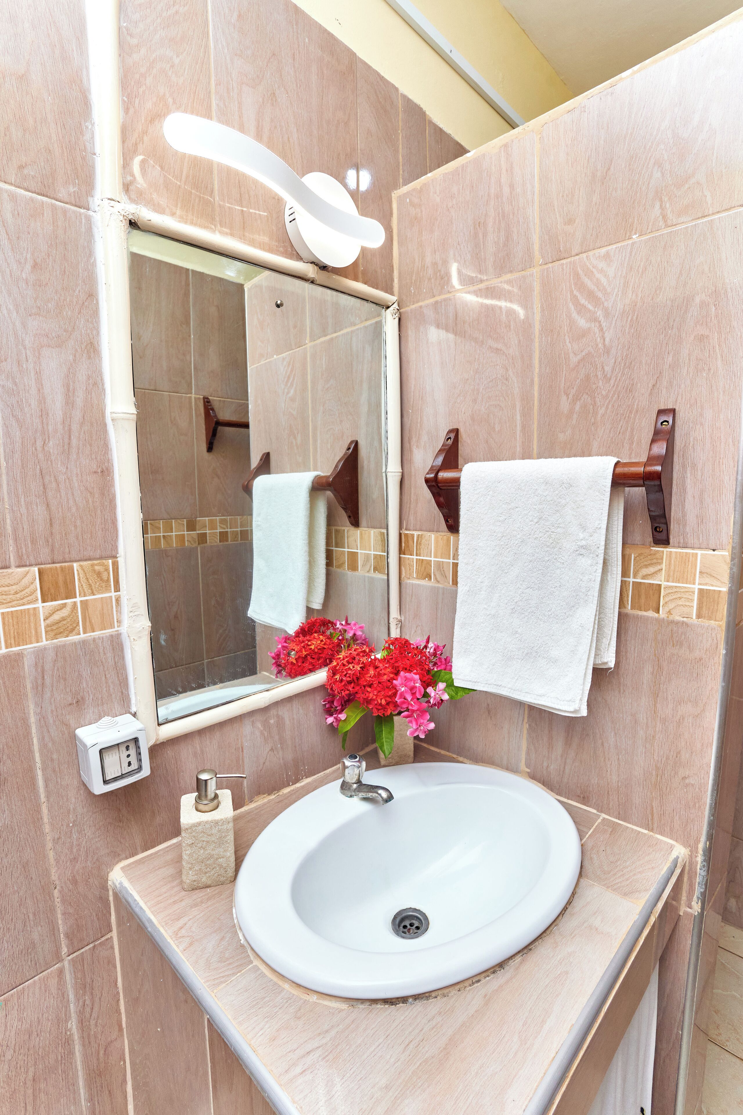 Un baño con lavamanos blanco, espejo y barra para toallas.