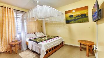 A room with a bed, a bedside table, a nightstand, a TV, and a painting on the wall.