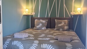 Een slaapkamer met een bed, twee bedlampen en een bedspread met een patroon.