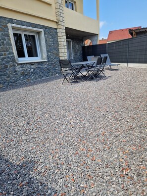 Eine Terrasse mit Tisch und Stühlen, eine Steinmauer und ein Fenster.