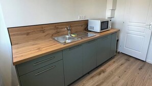 Een moderne keuken met een houten aanrecht, een inbouwspoelbak en een magnetron.
