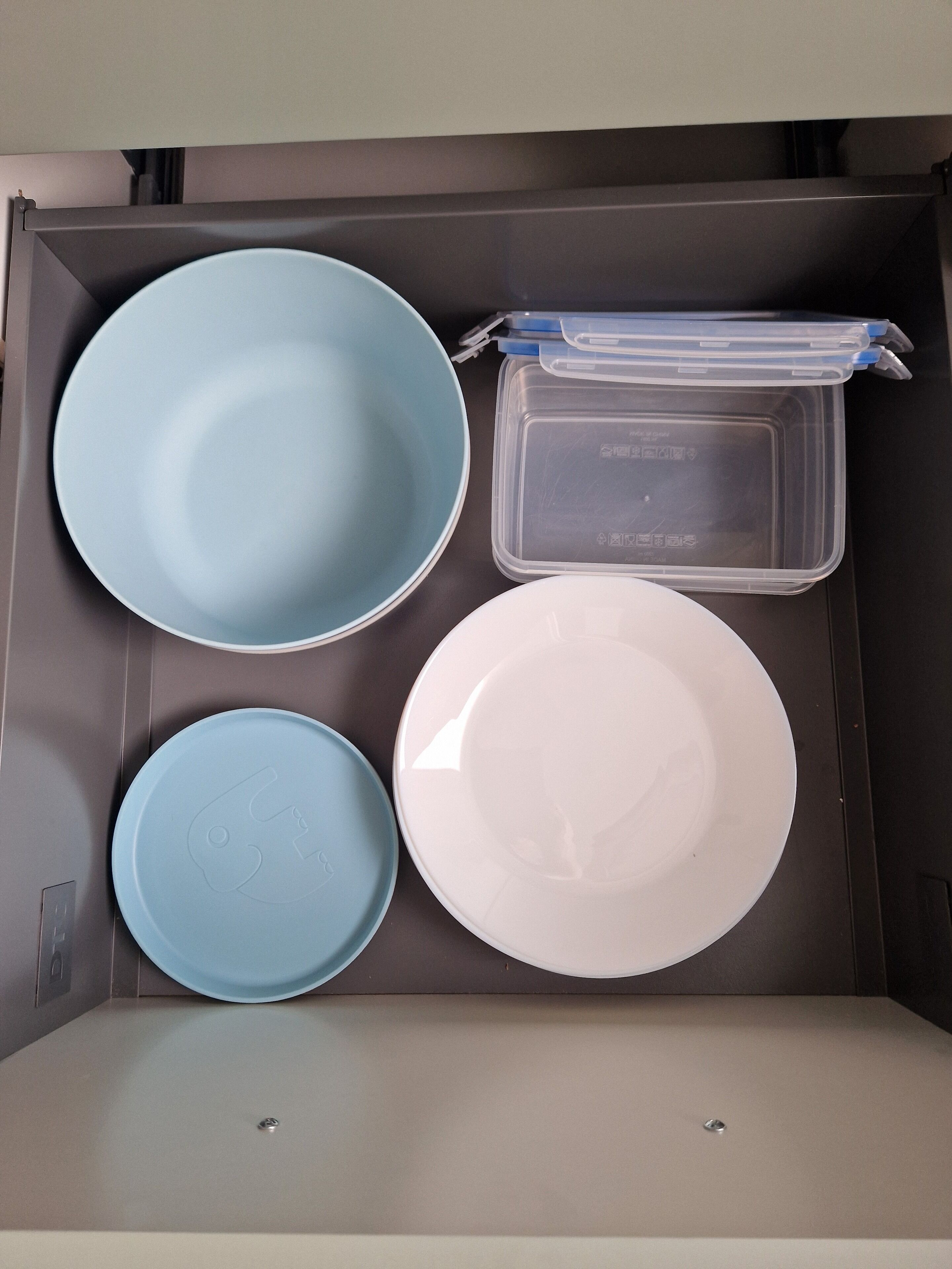 A storage box containing four plates and a plastic container.