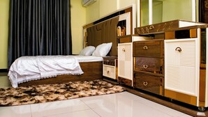 A bedroom with a bed, a wardrobe, a mirror, and a window with curtains. - Mvita Heights Retreat (Dar es Salaam)