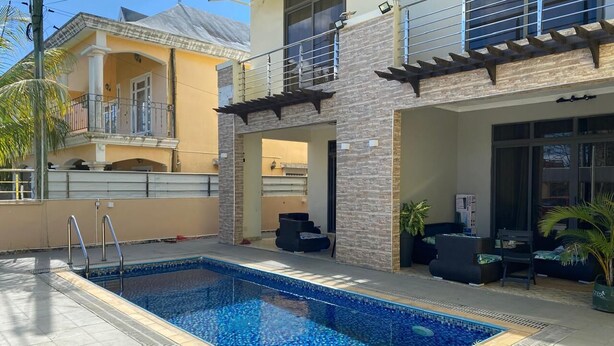 Une piscine rectangulaire dont les bords sont recouverts de carreaux, entourée d’une terrasse dallée.