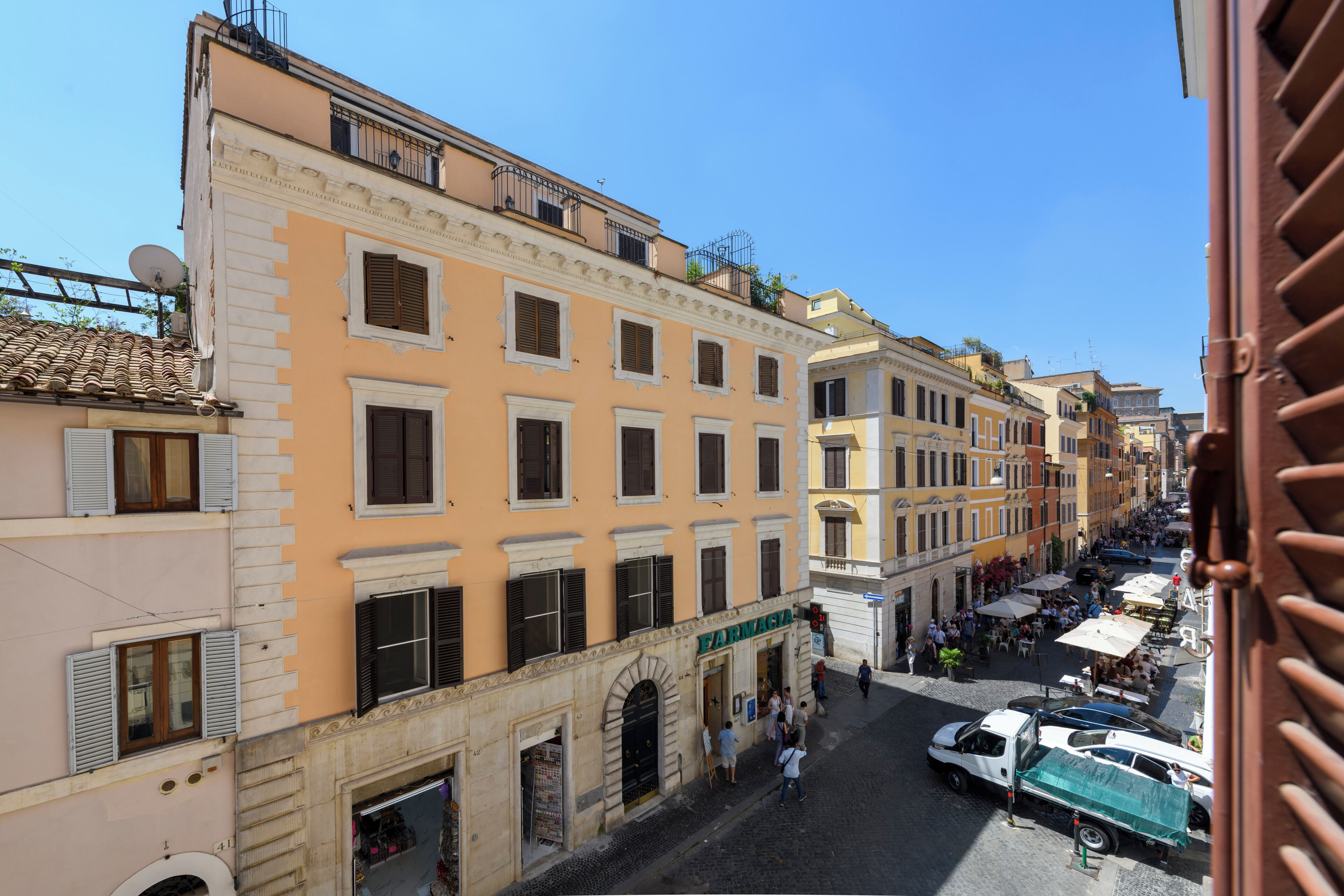 A street view of a historic European town with buildings featuring classic architecture, a pharmacy, and a cobblestone street.