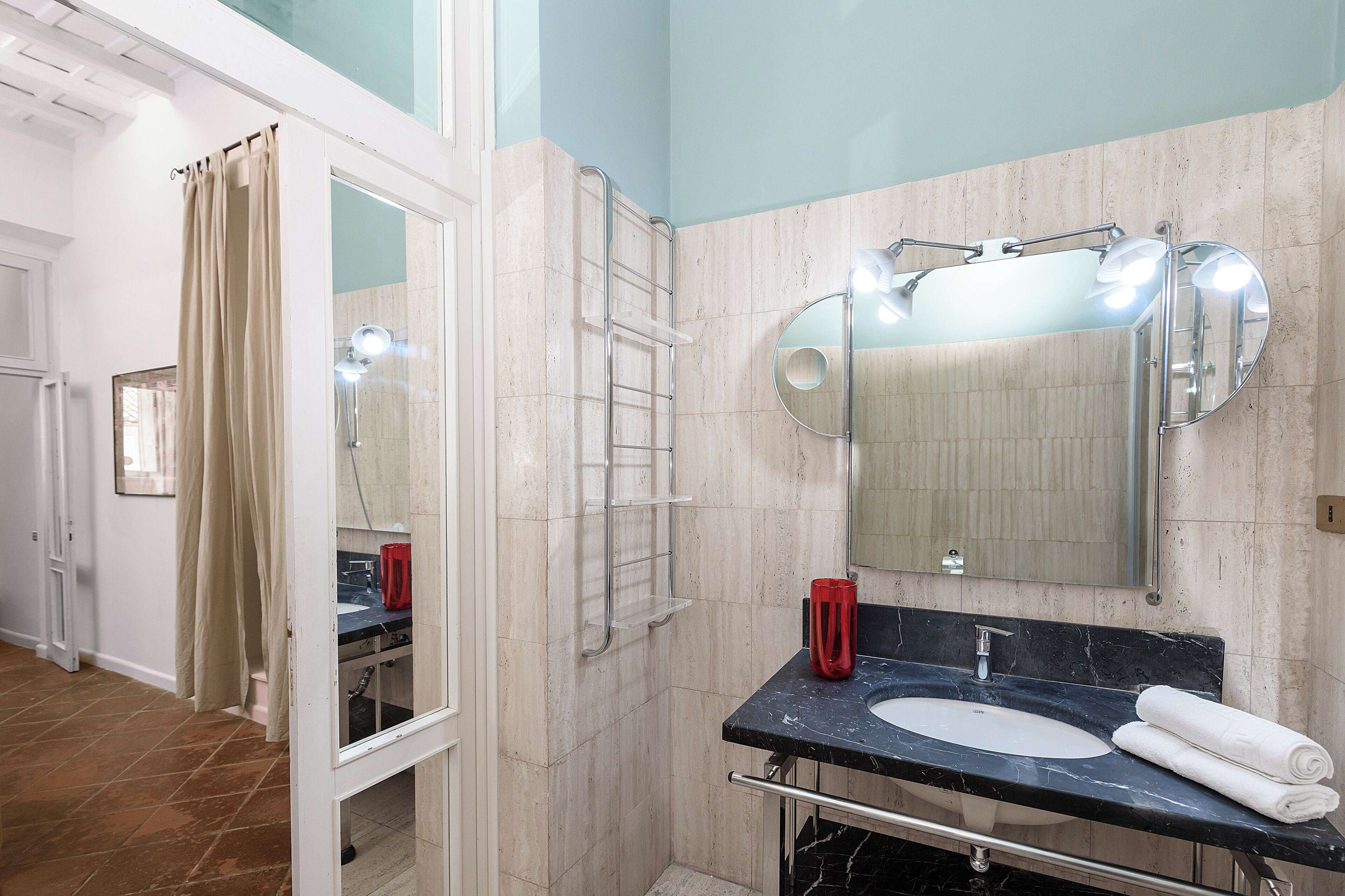 Une salle de bain équipée d’un lavabo, d’un miroir, d’une serviette et d’un espace douche.