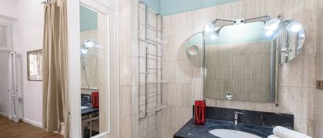 Une salle de bain équipée d’un lavabo, d’un miroir, d’une serviette et d’un espace douche.
