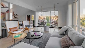 A modern living room with a sofa, chairs, a coffee table, and a hanging chair.