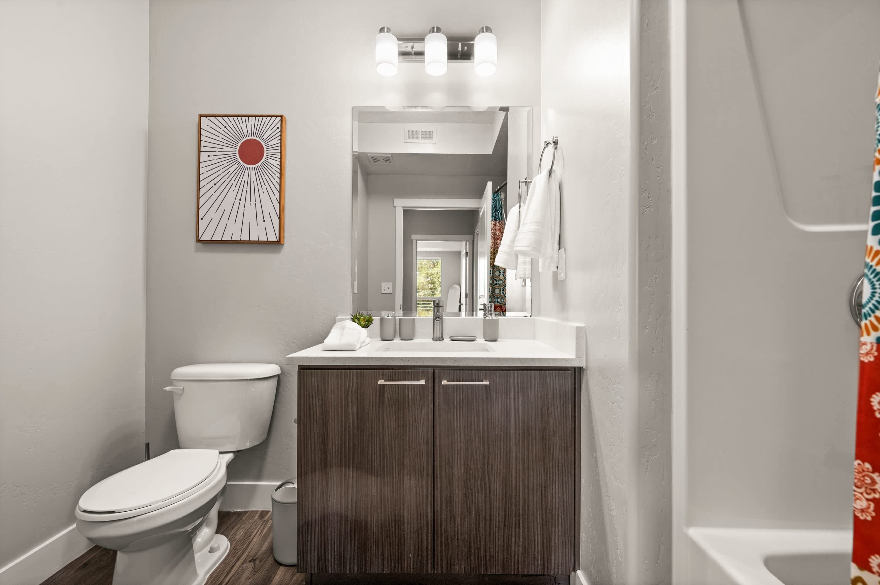 A bathroom with a toilet, vanity, sink, and shower curtain.