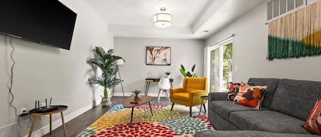 Una sala de estar moderna con un sofá gris, un tapete colorido con estampado y un sillón amarillo.
