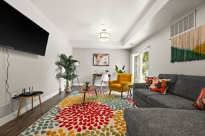 Una sala de estar moderna con un sofá gris, un tapete colorido con estampado y un sillón amarillo.