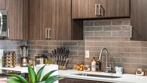 Una cocina moderna con armarios de madera oscura, un microondas de acero inoxidable, una licuadora y una cafetera.