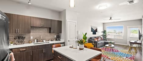Une cuisine moderne avec des meubles de couleur bois foncé, un plan de travail blanc et un îlot central.