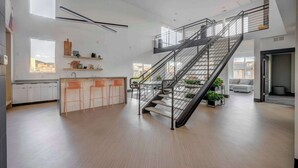 Une cuisine moderne avec un îlot central, un escalier et une vue sur la ville.