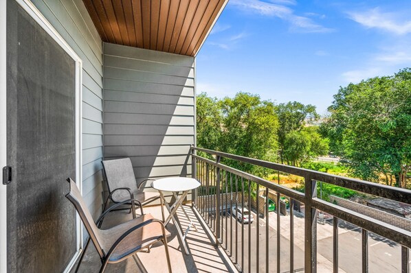 A balcony with a view of a parking lot and trees.