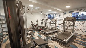 Ett gym med olika typer av träningsutrustning, inklusive löpband, crosstrainers och styrketräningsmaskiner.