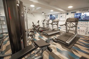 Een sportschool met diverse fitnessapparatuur, waaronder loopbanden, elliptische trainers en krachtapparaten.