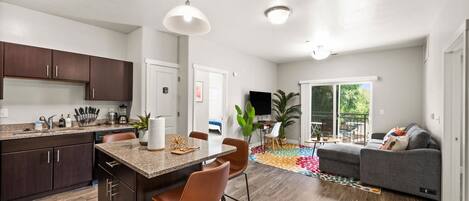 A modern kitchen with dark wood cabinets, a granite countertop, and a central island with bar stools.