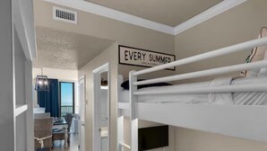 Une chambre avec des lits superposés, sur laquelle est accrochée une pancarte portant l’inscription : « CHAQUE ÉTÉ ÉTAIT UN ÉTÉ INOUBLIABLE ».