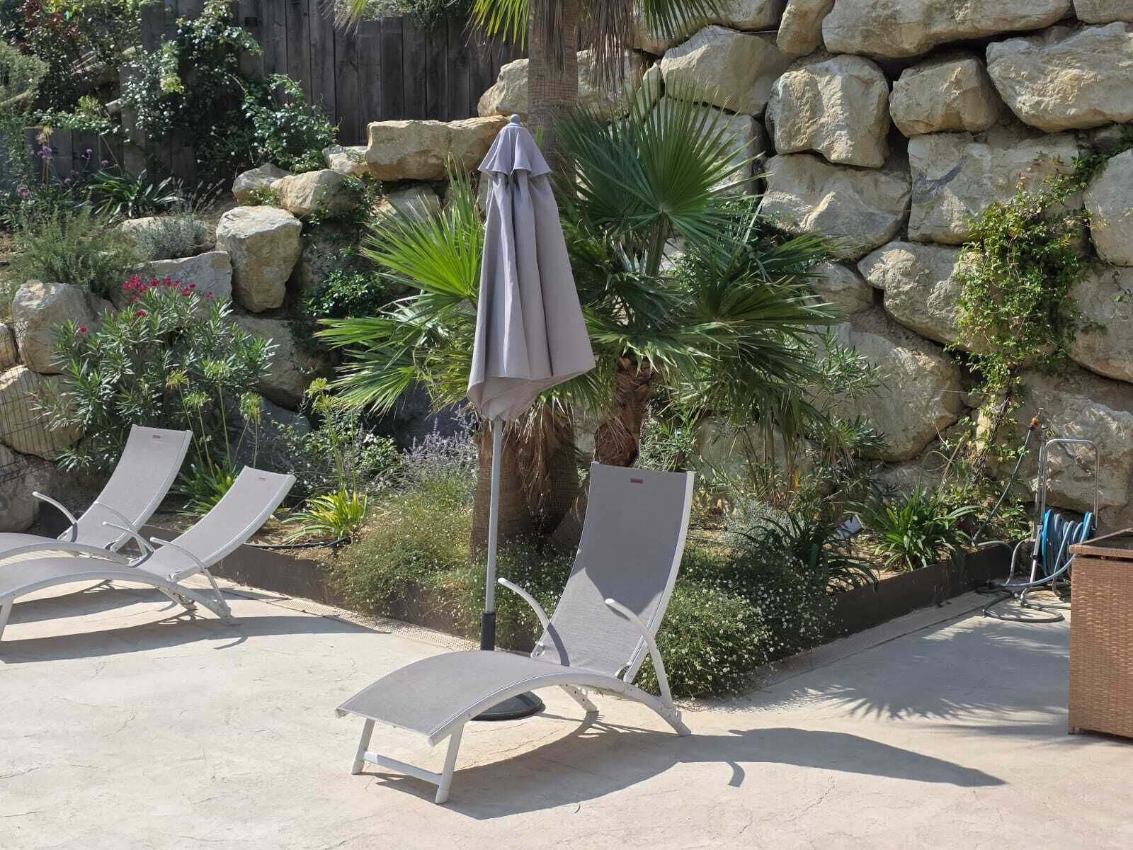 Un patio con dos sillones, un muro de piedra y diversas plantas.