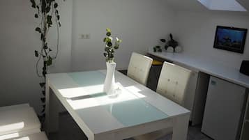 A modern kitchen with a skylight, a dining table with chairs, and a hanging plant.