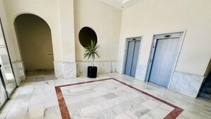 Eine großzügige Lobby mit Marmorboden, einer Zimmerpflanze und zwei Aufzügen.