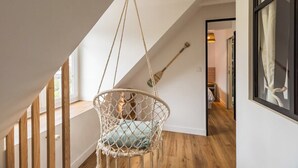 A macramé hanging chair in a spacious room with wooden floors and a sloped ceiling. - Charming House on Loguivy de la Mer harbor (Ploubazlanec)