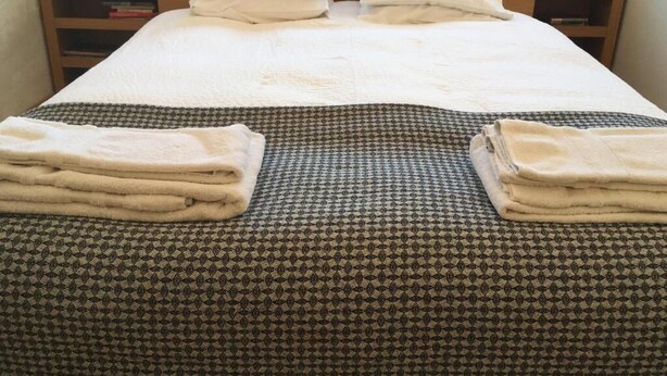A neatly made bed with white linens, a patterned bedspread, and two bedside tables with lamps.