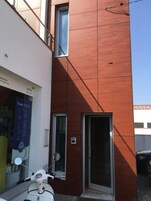 Un edificio moderno con fachada roja, puerta de entrada de vidrio y una patineta estacionada adelante.