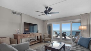 A spacious living room with a large flat-screen TV, a ceiling fan, and a view of the ocean through the sliding glass doors. - Sandy Key 433: 2 BR / 2BA Gulf Front Condo In Perdido Key, FL. Sleeps 6 (Pensacola)