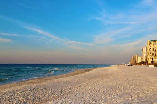 A beach with a sandy shore, ocean waves, and high-rise buildings in the background.