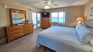 Une chambre à coucher avec un lit, une commode, un ventilateur de plafond et une vue sur l’océan par la fenêtre.