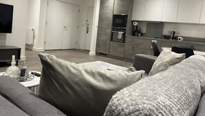 A modern living room with a grey sofa, a coffee table, and a TV. - Riverside Retreat in Barking (Barking)